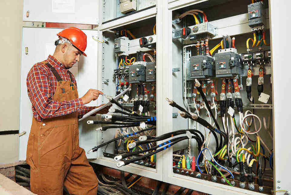 Električar popravlja kablove u strujnom ormanu